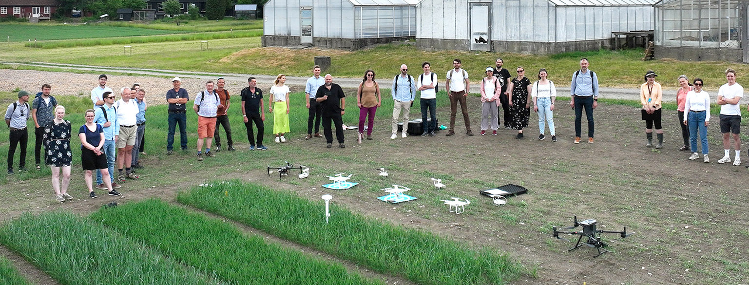 A group of people standing beside several drones on the ground. 