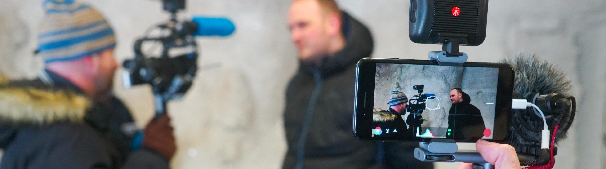 En mobilkamera med mikrofon filmar en man som intervjuas av en annan man med kamera