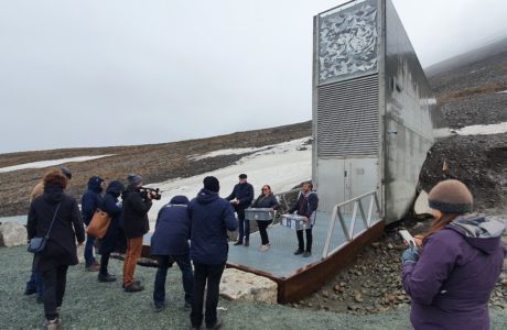 A group of people standing with their backs against the camera facing the Svalbard Global Seed Vault.