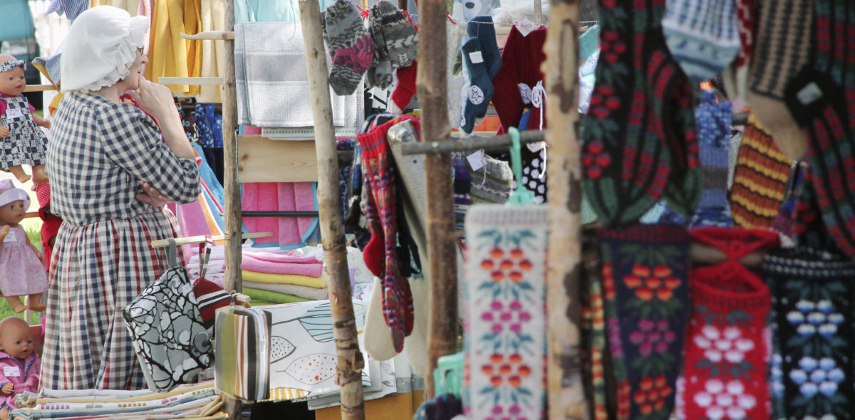 Market stand with colourful old fashioned woolen mittens in the foreground