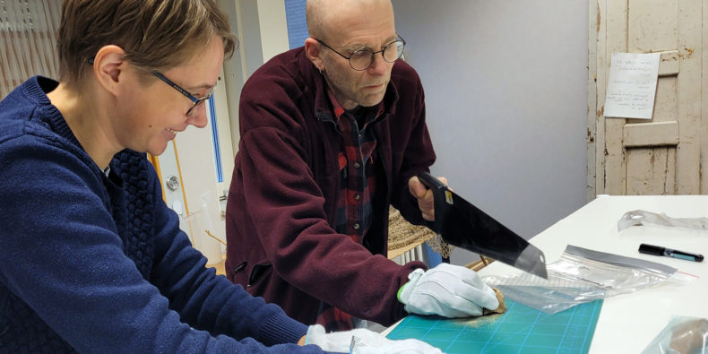 Två arkeologer vid ett arbetsbord sågar i gamla djurben för att få fram DNA-material