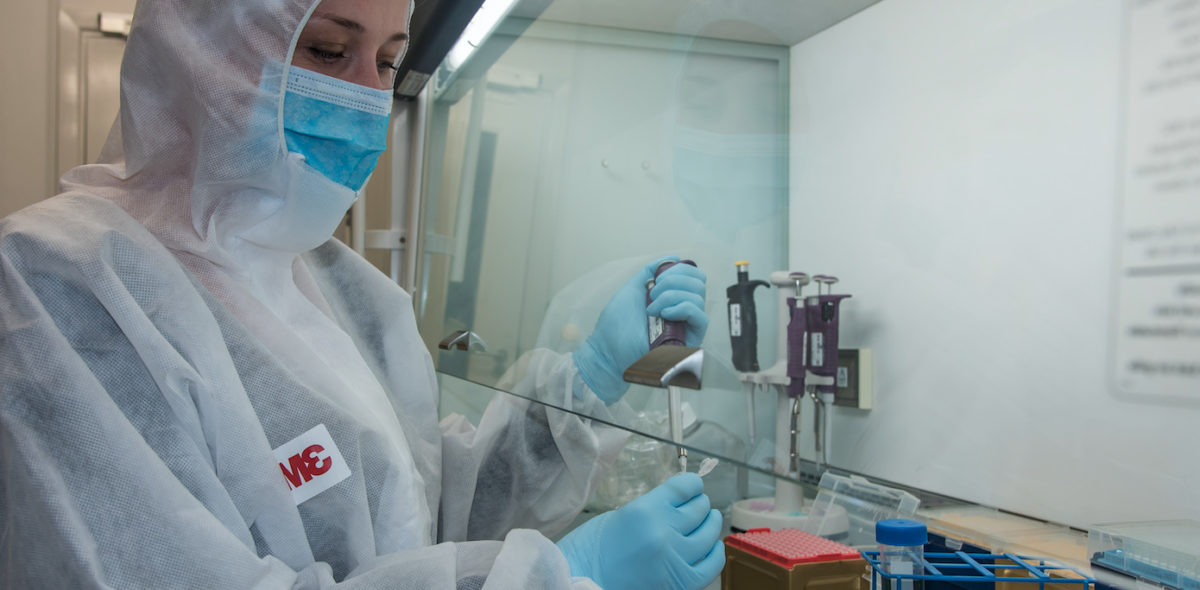 Person working in a laboratory analyzing DNA wearing protective clothing