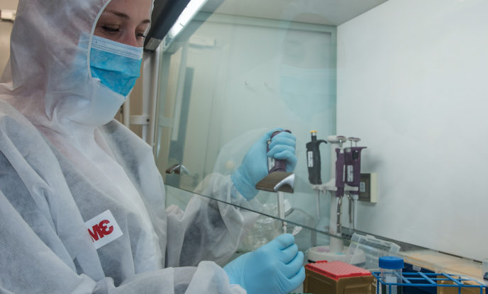 person i skyddsdräkt i laboratorium jobbar med DNA-prover