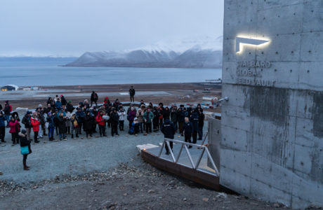 Seed Vault exterior to the right and the mountains in the background, People standing in front of the Seed Vault.